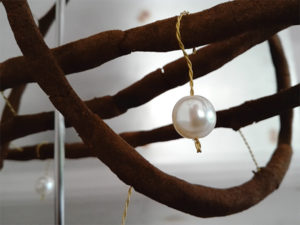 Close up of a pearl hanging on incense wire.