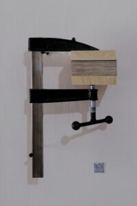 A painting compressed between a glue clamp.